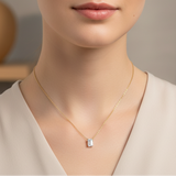 Create a styled fashion shot of a female model in an elegant, contemporary setting that suggests versatility and effortless sophistication. The model is captured in a mid-shot, slightly turned to showcase the Emerald Elegance necklace resting gracefully on