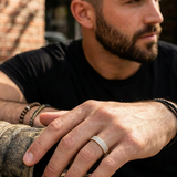 Close-up of Tessera unisex diamond band ring in 10K yellow gold on a male model's hand, showcasing a slim band and modern style from a cool angle.