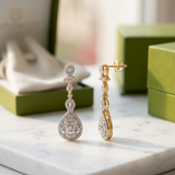 Ambery 14K yellow gold diamond drop earrings displayed on textured marble, illuminated by warm natural light, emphasizing craftsmanship and sparkle.