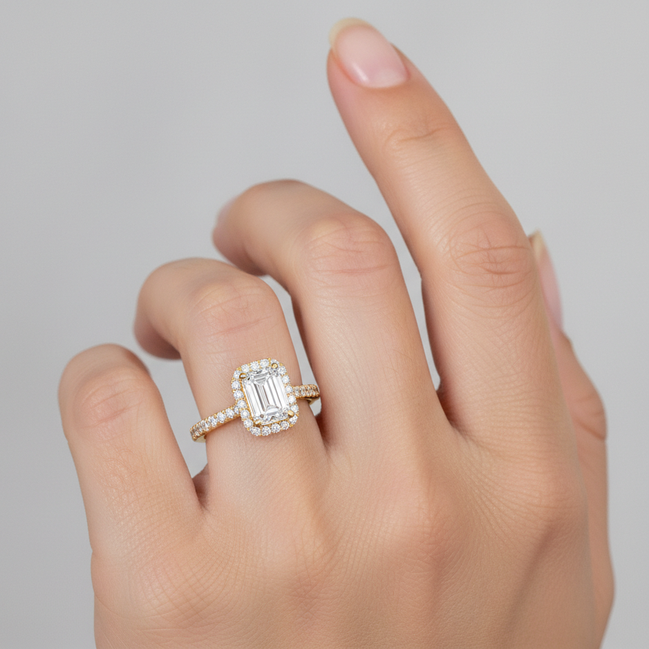 Photorealistic jewelry hand model shot of an emerald-cut halo engagement ring. Average ring size US 6.5. Center stone shown at intentionally conservative visual scale (approx 7.0–7.2 × 5.0–5.2 mm), thin halo that does not add width, band ~1.5 mm. Wide fram