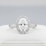 A highly detailed, studio-shot of the Idalia 14K White Gold Oval Lab Grown Diamond Halo Engagement Ring, captured with a macro lens at 100mm focal length. Softbox lighting creates gentle, even illumination highlighting the 1.9 Ct oval lab-grown diamond's b