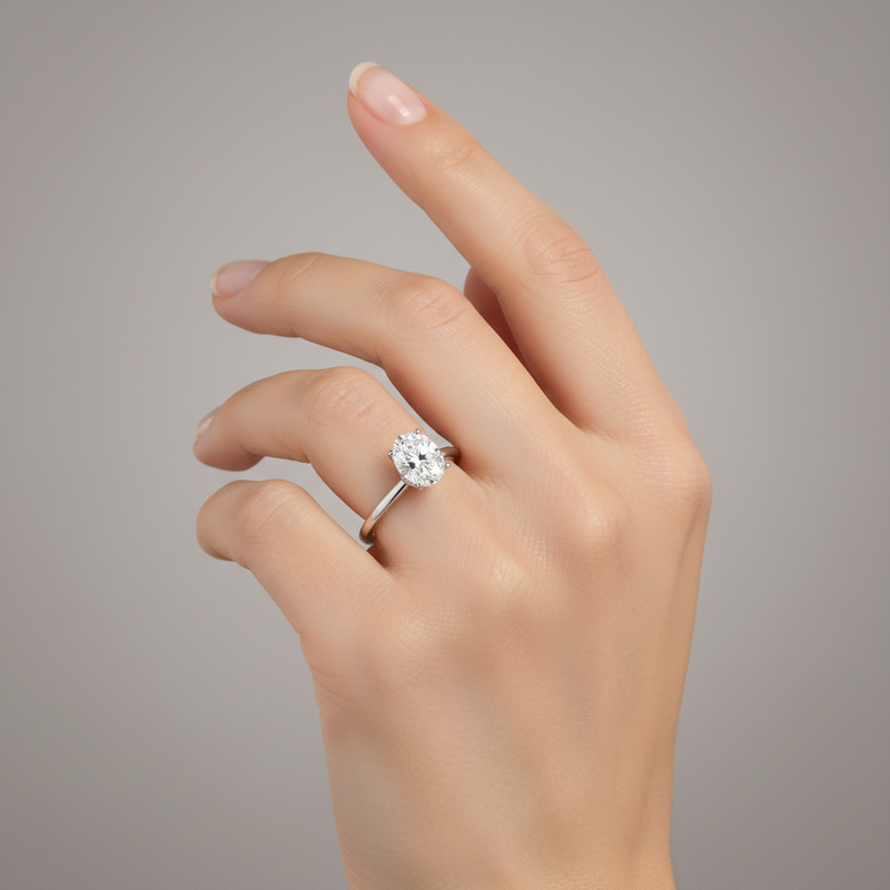 studio soft light image of ring on female model hand. Oval solitaire center stone. The oval center stone is only 10mm in length and 6mm in width. Make the ring smaller than it is