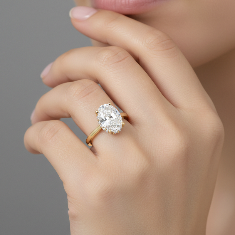Studio shot of female hand showcasing Hera lab grown diamond ring in soft lighting, with focus on oval center gemstone.