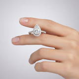 female hand model image, studio setting scene. pear solitaire diamond is 8mm length and 6 mm width. make the ring smaller than it is. Focus on pear shaped center stone detail