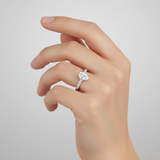 Capture a close-up, studio-quality image of a female hand elegantly wearing the Rasha 14K White Gold Pear Lab Grown Diamond Hidden Halo Engagement Ring. Use diffused daylight studio lighting with a subtle rim light to highlight the pear-shaped solitaire di