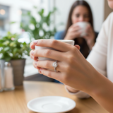 female hand model image, lifestyle setting scene. round halo diamond is 6.5 mm. make the ring smaller than it is