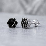 Close-up of 1.1ct black diamond cluster studs in 10K white gold, highlighting their intricate design and sparkling diamonds with soft natural lighting.