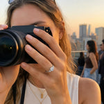 Cushion cut lab-grown diamond engagement ring in 14K white gold on a hand during a rooftop sunset gathering, capturing a natural, candid moment.