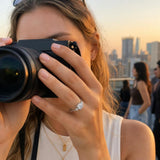Cushion cut lab-grown diamond engagement ring in 14K white gold on a hand during a rooftop sunset gathering, capturing a natural, candid moment.