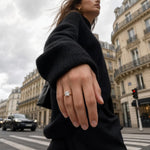 Close-up of Genoveva 14K yellow gold engagement ring with princess cut lab grown diamond and hidden halo, in street fashion setting with Parisian architecture