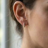 High-resolution image of 11.85mm gold diamond huggie hoops on a model, showcasing craftsmanship, sparkle, and minimalist elegance.