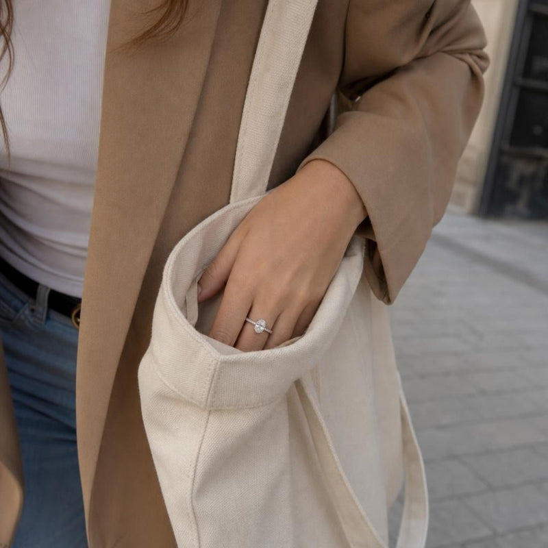Model's hand with engagement ring inside tote bag during fashion shoot on city sidewalk.