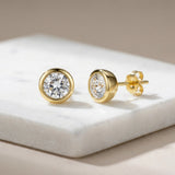 A dramatic studio shot of the Alisha diamond studs presented on a textured white marble slab with subtle shadows for depth. The earrings are illuminated with HDR studio lighting, creating a high-contrast scene that enhances the clarity and fire of the diam