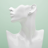 Arrange a staged, studio-focused shot of the Elaria earrings displayed on a minimalist female bust mannequin, set against a pastel mint green backdrop ideal for Valentine’s Day. Use a softbox to evenly diffuse a gentle HDR studio light that enhances the sp