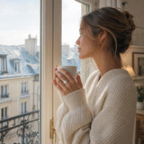 Elegant 14K yellow gold oval lab-grown diamond halo engagement ring with side stones, presented in a lifestyle scene overlooking Paris rooftops.