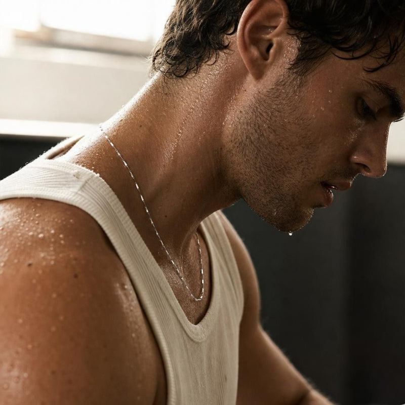 Close-up of a 925 sterling silver bar chain necklace resting on the neck of an athletic man.