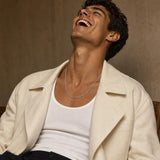 Close-up of a masculine model wearing a classic 2.1mm sterling silver box chain necklace against a taupe studio wall.