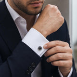 Close-up of a man wearing sterling silver emerald cut black spinel cufflinks while adjusting his formal suit shirt sleeve.