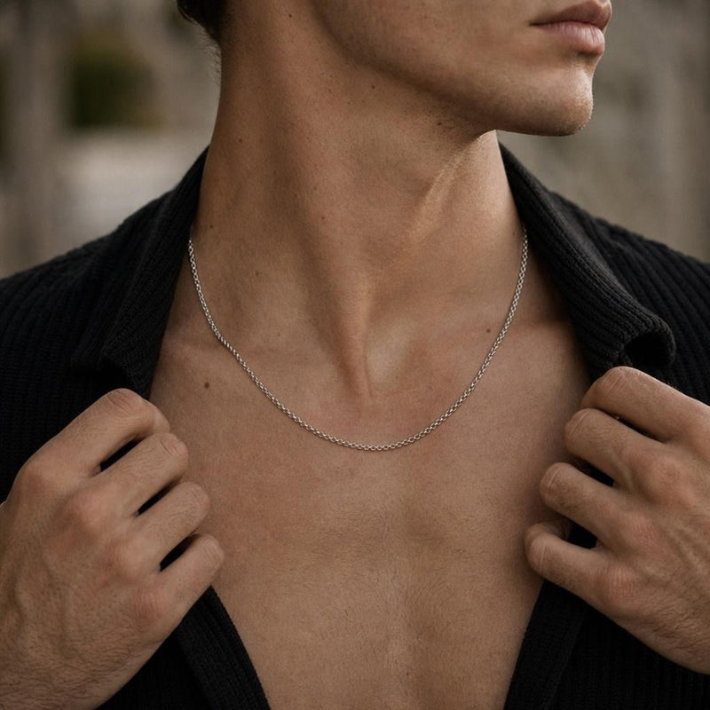 Detailed close-up of a masculine sterling silver round rolo chain resting on a man's neck and chest.