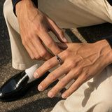A detailed shot of a Kairo round-cut black spinel ring on a man's finger, featuring a sterling silver band.