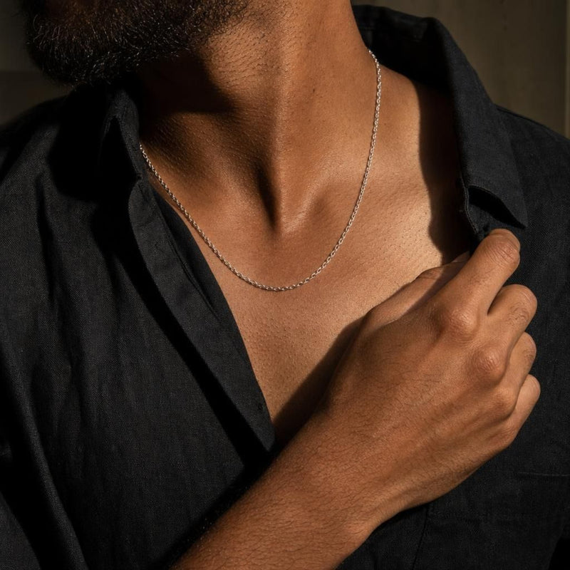 Naoki sterling silver diamond-cut cable chain necklace worn by a man in a black linen shirt.