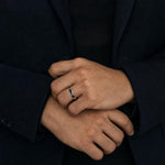 Rei princess cut black spinel ring in 925 sterling silver worn on a man's hand with a structured dark jacket.