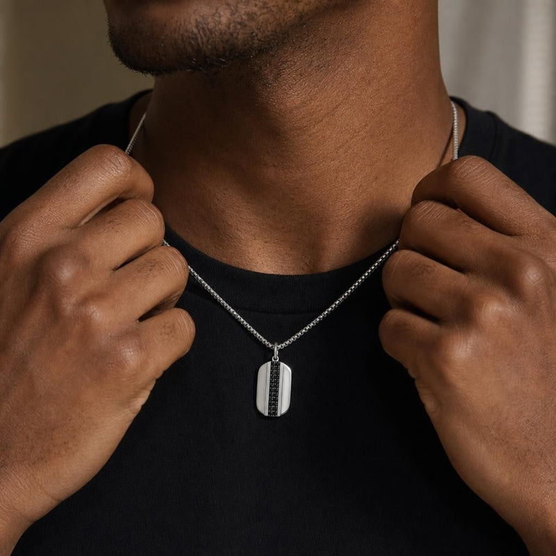 Sterling silver dog-tag pendant with pavé black spinels worn by a man in a black t-shirt, held by his hands.