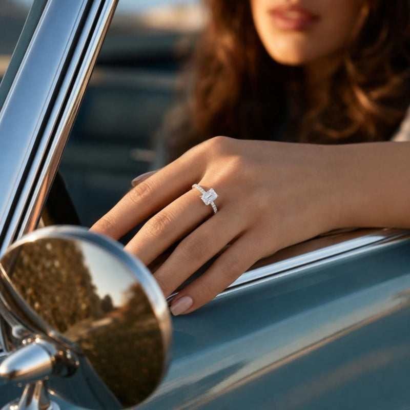 Emerald cut lab grown diamond engagement ring on hand touching vintage car window frame with reflection and golden-hour sunlight